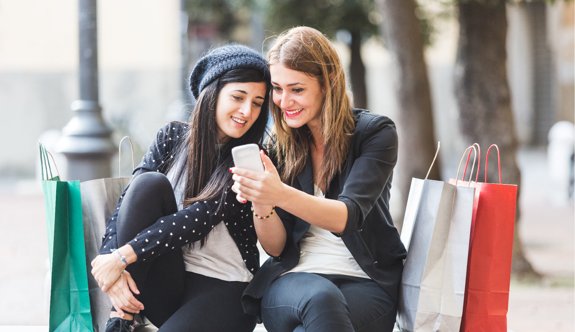 two women smiling as they look at a phone