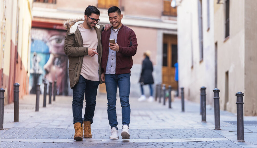 Two men walking together and looking at a phone